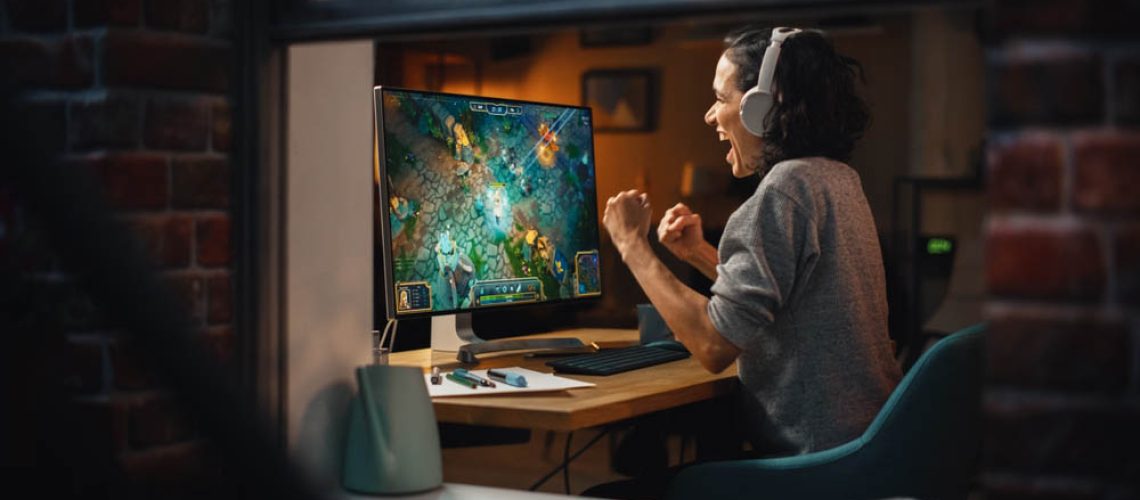 Cheerful Female Gamer Playing Online Video Game on Personal Computer. Professional Woman Player Enjoying Fantasy RPG and Celebrating Victory. Role Playing Character Casting Magic Spells. Window View.
